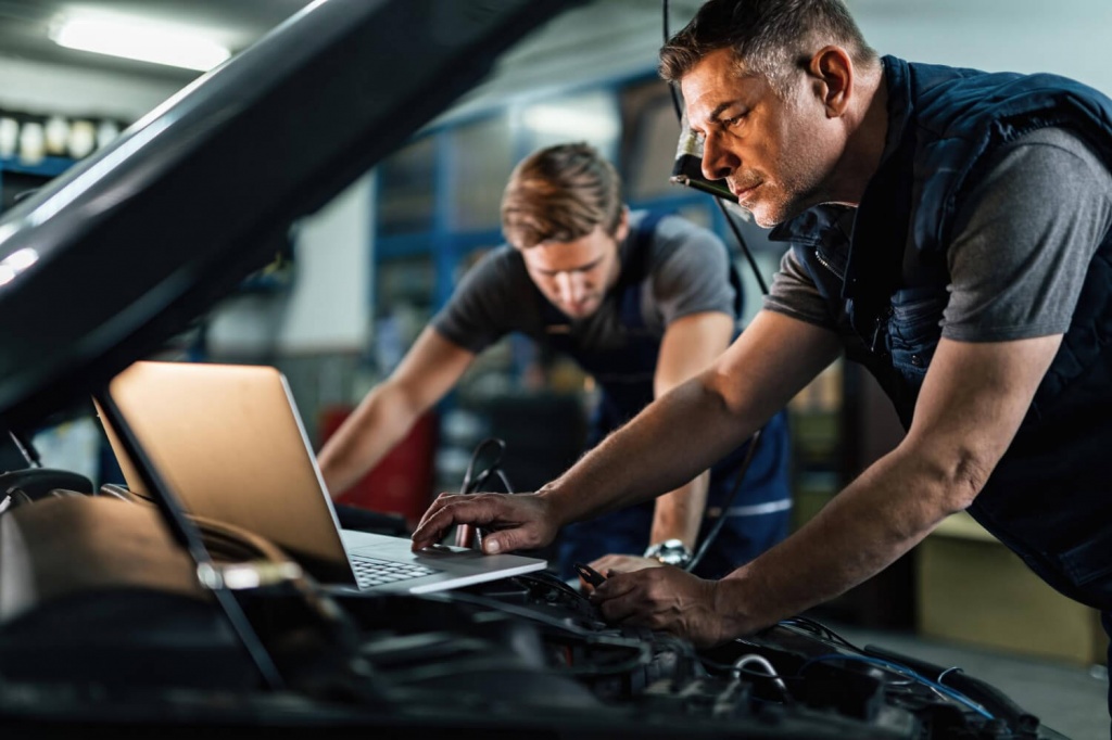 mid-adult-mechanic-using-computer-doing-car-diagnostic-with-his-coworker-auto-repair-shop.jpg